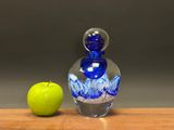 an apple and a blue glass bottle sitting on a table