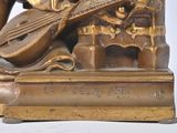 bronze statue of a man playing a musical instrument on a table