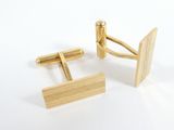 pair of gold cufflinks with a wooden bar on a white background