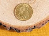 a gold coin sitting on top of a piece of wood