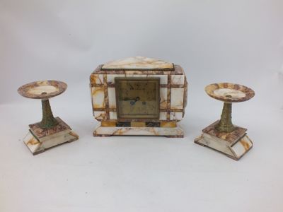 une petite horloge posée sur une table, à côté de deux bougies