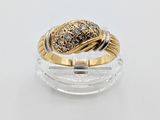 une photo d'une bague en or et diamants posée sur une surface transparente