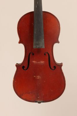un vieux violon posé sur une table près d'un mur blanc