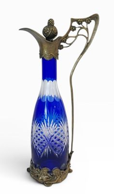 pichet en verre bleu et blanc muni d'une anse en métal, sur fond blanc