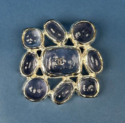 a close up of a broochle with blue stones on a blue surface