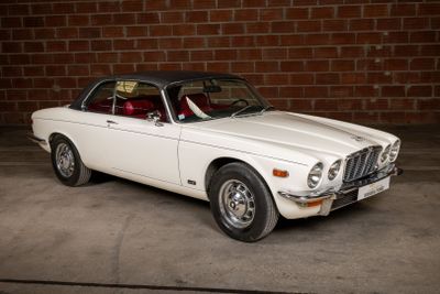 a white car that is parked in front of a brick wall