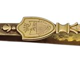 a gold tie bar that has a picture of a coat of arms on it