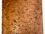 un vieux livre à la couverture marron posé sur une table blanche