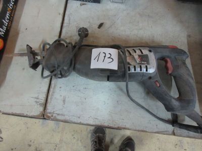 une perceuse filaire posée par terre à côté d'une paire de chaussures