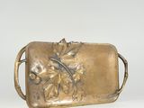 gold plate with a design of leaves and acorns on it