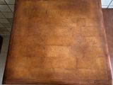 a wooden table with a brown top on a tiled floor