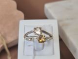 une boîte blanche sur laquelle est accrochée une bague et qui contient une bague en or