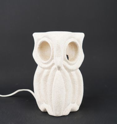 a white ceramic owl lamp with a white cord on a black background