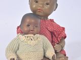 two dolls sitting next to each other on a white surface