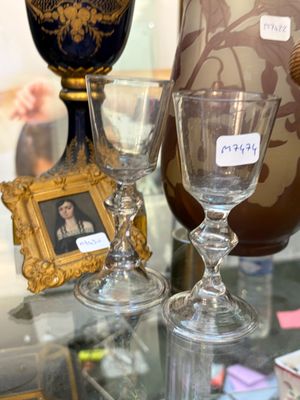 deux verres à vin et un vase posés sur une table en verre