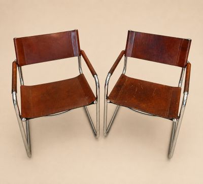 deux fauteuils en cuir marron aux pieds chromés, sur fond beige