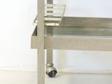 a stainless steel table with a glass top on wheels