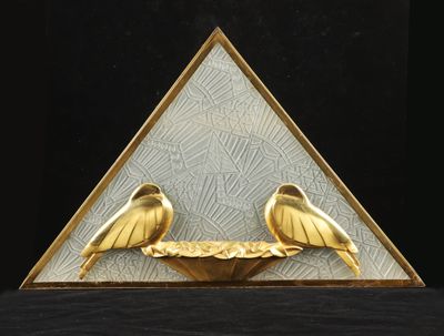 deux oiseaux dorés posés sur une assiette dorée devant un fond noir