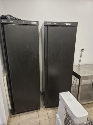 two black refrigerators sitting next to each other in a kitchen