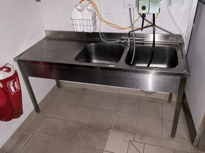 un lavabo dans des toilettes publiques, avec un sac rouge posé par terre
