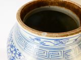un vase bleu et blanc posé sur une surface blanche