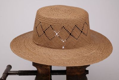un chapeau de paille troué posé sur un support