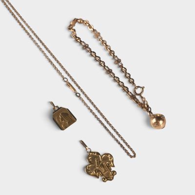 un gros plan sur un collier en or et deux autres objets posés sur une surface blanche