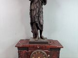 une statue de femme tenant une horloge sur une table