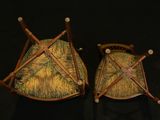 pair of wooden chairs with green and yellow cushions on a black background