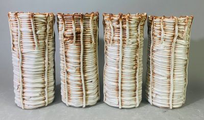 quatre vases sont alignés sur une surface grise