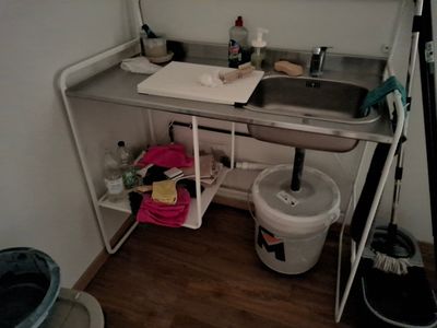 a sink and a trash can in the corner of a room