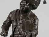 bronze statue of a boy with a hat and a bag