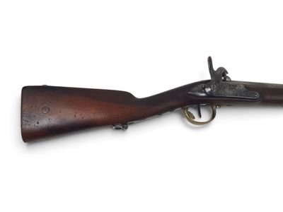 un vieux fusil exposé sur une surface blanche