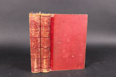 an old red book sitting on top of a table next to a black background
