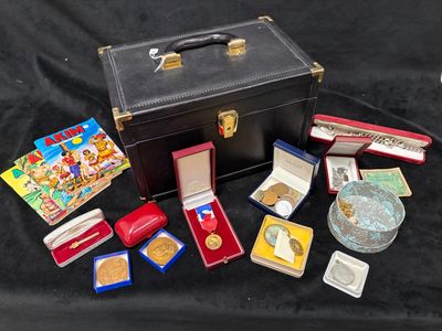 une valise noire sur laquelle sont posées des médailles d'or et d'autres objets