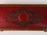 an old red and gold box with a decorative design on it