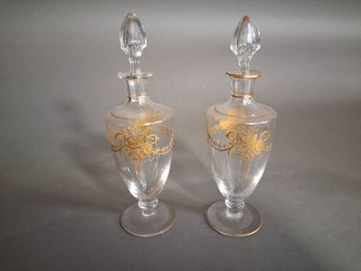 two clear glass vases with gold designs on them sitting on a table