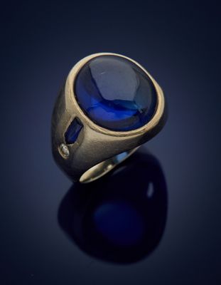 a close up of a gold ring with a blue stone