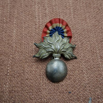 un petit objet en métal orné d'une fleur rouge, blanche et bleue