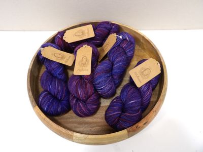 purple and blue yarn in a wooden bowl on a white surface