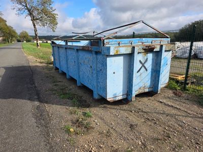 une benne bleue garée au bord de la route