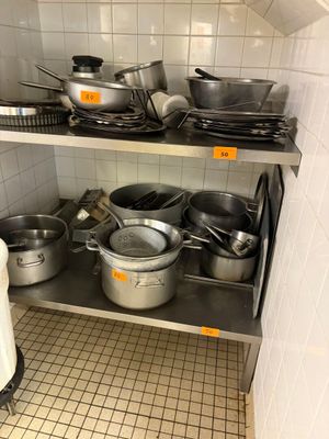 de nombreuses casseroles et poêles sur les étagères de la cuisine