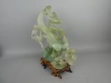 une statue représentant un dragon posé sur un rocher, sur un fond blanc