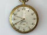 une montre de poche en or sur une surface blanche
