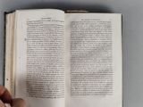 a hand that is holding an open book on a table