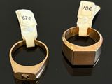 two gold rings with a price tag on them sitting on a black surface
