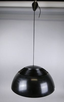 une lampe noire suspendue au plafond, sur laquelle se trouve une araignée