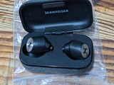 a pair of ear buds in a case on a wooden table