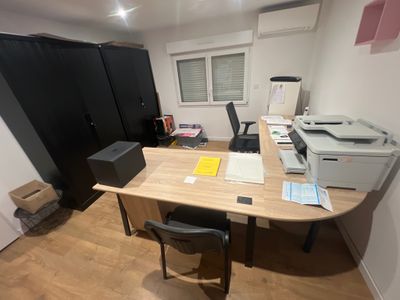 un bureau sur lequel se trouve une imprimante, dans un coin de la pièce