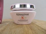 a jar of kerastase cream on a table next to a pink vase